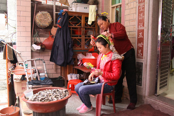 This hairstyle is symbolic and is meant to ward off evil spirits. In winter, the laurel can last for three days, but it only lasts for two in summer. When the women sleep at night, they put the garland into water to keep it fresh. (CRIENGLISH.com/Luo Chun)