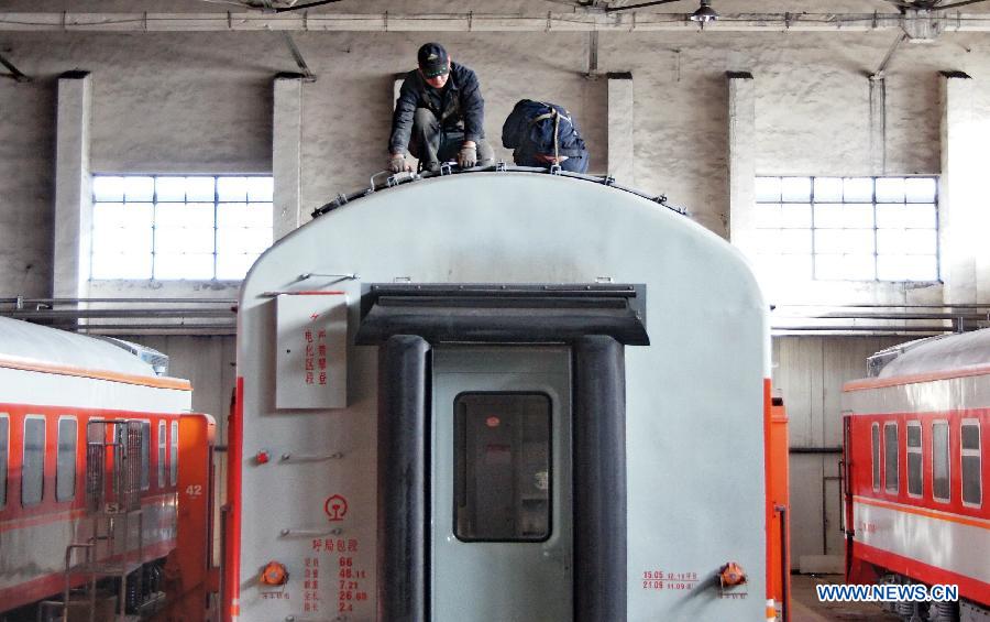 Two workers of the Baotou vehicle section of the Hohhot Railway Bureau repair a vehicle in Baotou, north China's Inner Mongolia Autonomous Region, Nov. 29, 2012. Facing the low temperatures, strong winds and snowfalls since winter, the Hohhot Railway Bureau has organized all its departments to guarantee the rail transport in winter, including activities like strengthening vehicle scheduling and security inspection during on-site operations. (Xinhua/Zhao Tingting) 