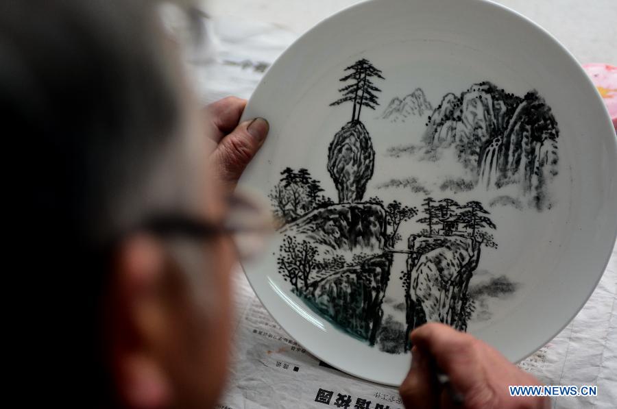 Bian Xiping, inheritor of intangible cultural heritage ceramic arts and crafts, paints on a ceramic plate by using traditional skills in Huating County, northwest China's Gansu Province, Nov. 29, 2012. 