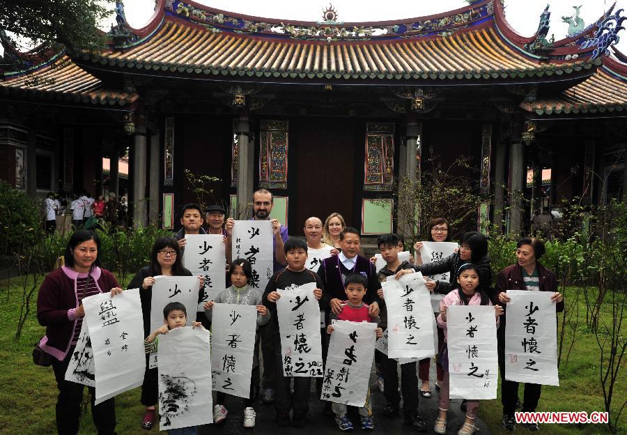 Tourists pose for pictures with their calligraphy works during a Chinese calligraphy experience activity at Taipei Confucius Temple in Taipei, southeast China's Taiwan Province, Dec. 2,2012. (Xinhua/Wu Ching-teng)