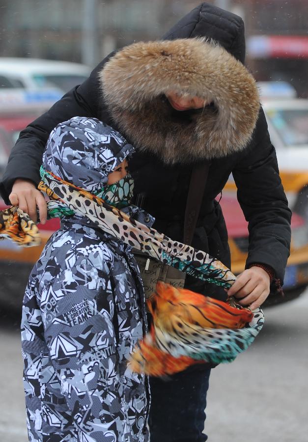 A citizen ties scarf for her child in Changchun, capital of northeast China's Jilin Province, Dec. 9, 2012. Most part of the province received a snowfall on Sunday. (Xinhua/Lin Hong)  