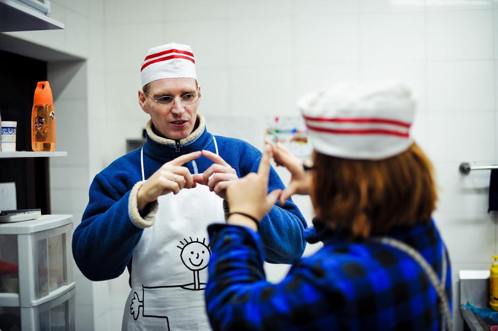 Uwe Brutzer (L) communicates with his Chinese student Jin Jing, a deaf-mute girl, at the "Bach's Bakery" in Changsha, capital of central China's Hunan Province, Feb. 9, 2012.(Xinhua/Bai Yu)