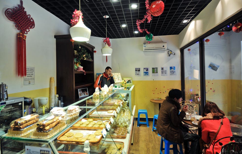 Uwe Brutzer (back) answers the phone at his "Bach's Bakery" in Changsha, capital of central China's Hunan Province, Feb. 7, 2012.(Xinhua/Bai Yu)