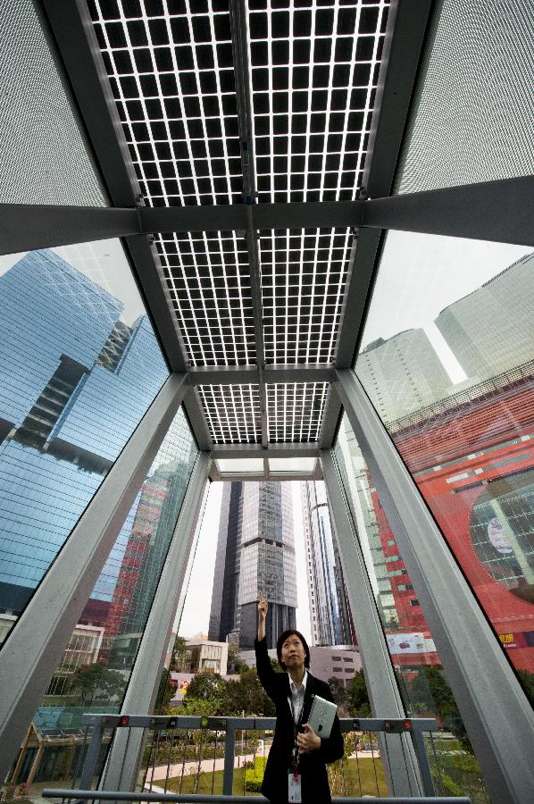 A staff member introduces the photovoltaic panels of Hong Kong's first zero-carbon building ZCB in Hong Kong, south China, Dec. 17, 2012. The building, which generates on-site renewable energy more than operation needs from photovoltaic panels and biodiesel tri-generation system and exports surplus energy to offset embodied energy of its construction process and major structural materials, will be opened to the public on Jan. 5, 2013. (Photo/Xinhua) 