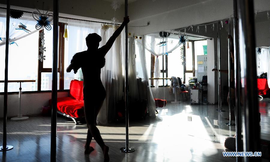 Xiao Zhao, a pole dance instructor, practises in a dance studio in Changchun, capital of northeast China's Jilin Province, Dec. 19, 2012. (Xinhua/Xu Chang) 