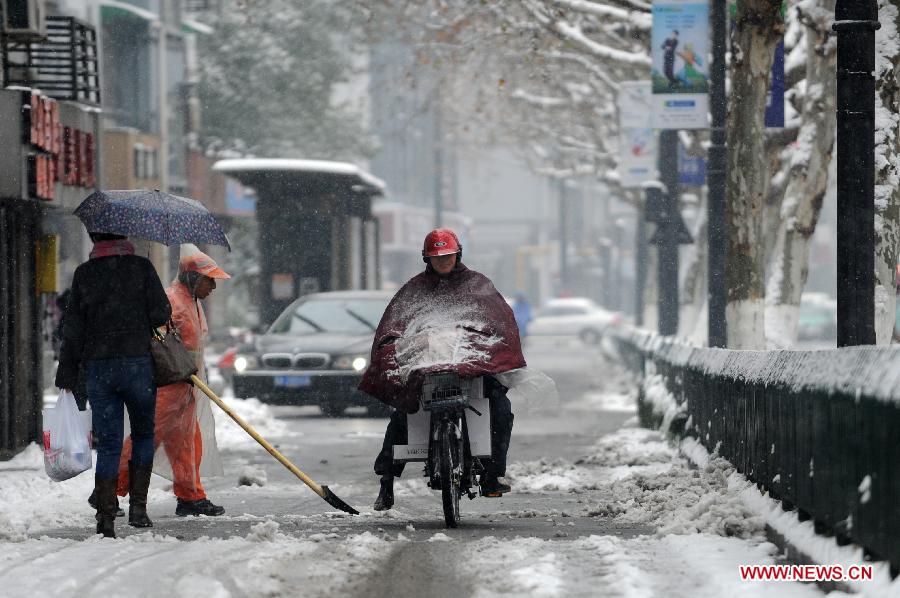 Citizens make their way on a snow-covered road as a sanitationman clears the snow in Hangzhou, capital of east China's Zhejiang Province, Jan. 4, 2013. Many areas in Zhejiang received snowfalls on Friday. The local meteorological authority issued an orange alert for icy roads on Friday morning, warning the possible disruption which the continued snow might cause to traffic, power supply and agriculture. (Xinhua/Ju Huanzong)