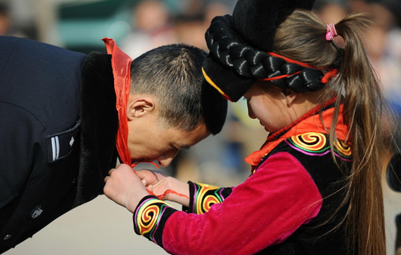 A student thanks Zhu Dong for his help by placing a red scarf around his neck at Ersaixiang Primary School, Yuexi county, Southwest China's Sichuan province, on Jan 8, 2013. Zhu, a 44-year-old railway policeman, has been helping students for the past seven years in his spare time, donating clothes and other daily necessities worth more than 500,000 yuan ($80,450). (Photo/Xinhua)