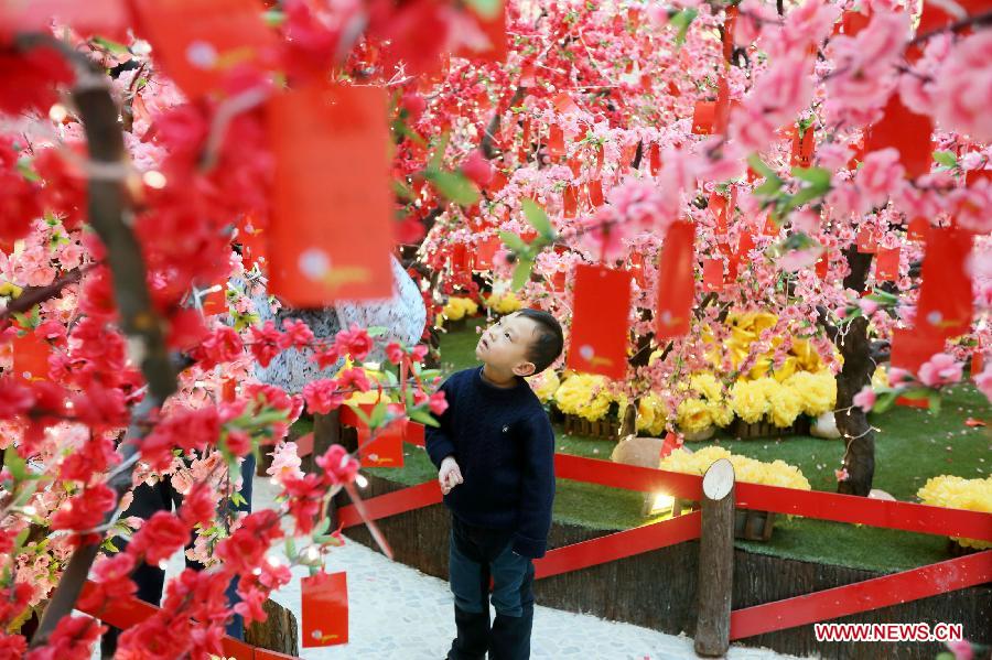 A little boy views the cards with people's New Year wishes written on them under a wishing tree at a shopping mall in Wangfujing, a commercial area in Beijing, capital of China, Jan. 26, 2013. (Xinhua/Luo Wei) 