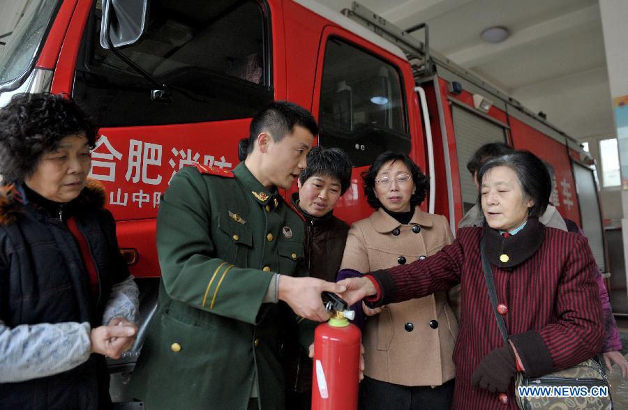 Firefighter Wang Mei (2nd L) teaches retired workers how to use a fire extinguisher at a fire brigade in Wulidun Community of Hefei, capital of east China's Anhui Province, Jan. 30, 2013. A group of community workers and retired staff members visited Wulidun fire brigade to celebrate the upcoming Spring Festival with the firefighters here on Wednesday. (Xinhua/Guo Chen) 