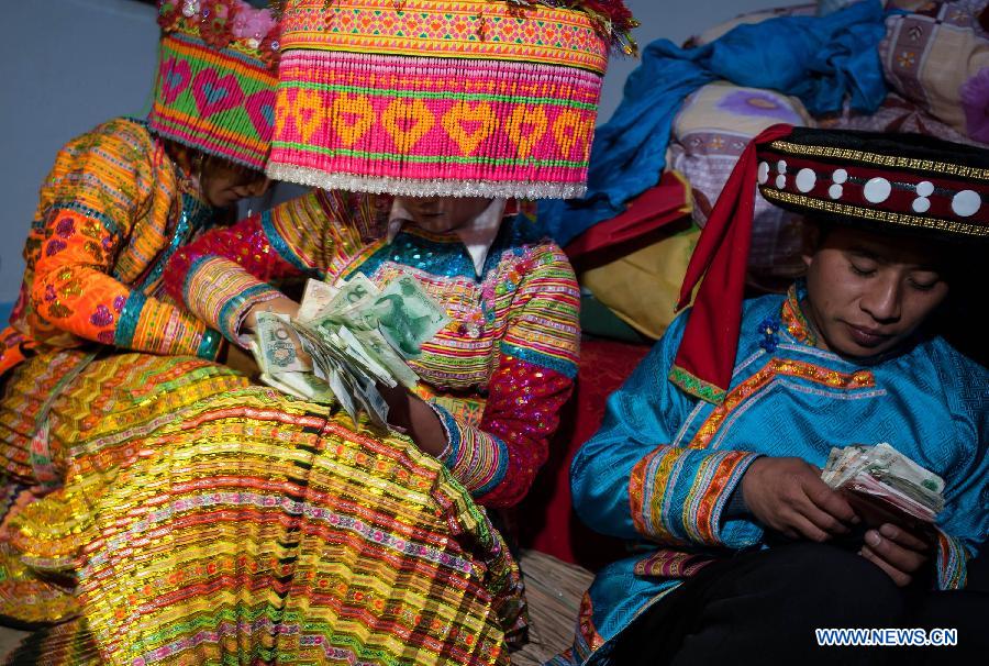 Bride Gu Hongyan (2nd R) and bridegroom Lan Xiaoxiang (R) compete to count their cash gifts during a traditional wedding ceremony of Lisu ethnic group in Xinyu Village of Dechang County, southwest China's Sichuan Province, Jan. 31, 2013. It is believed that the winner of the competition will have the final say on family affairs. (Xinhua/Jiang Hongjing)