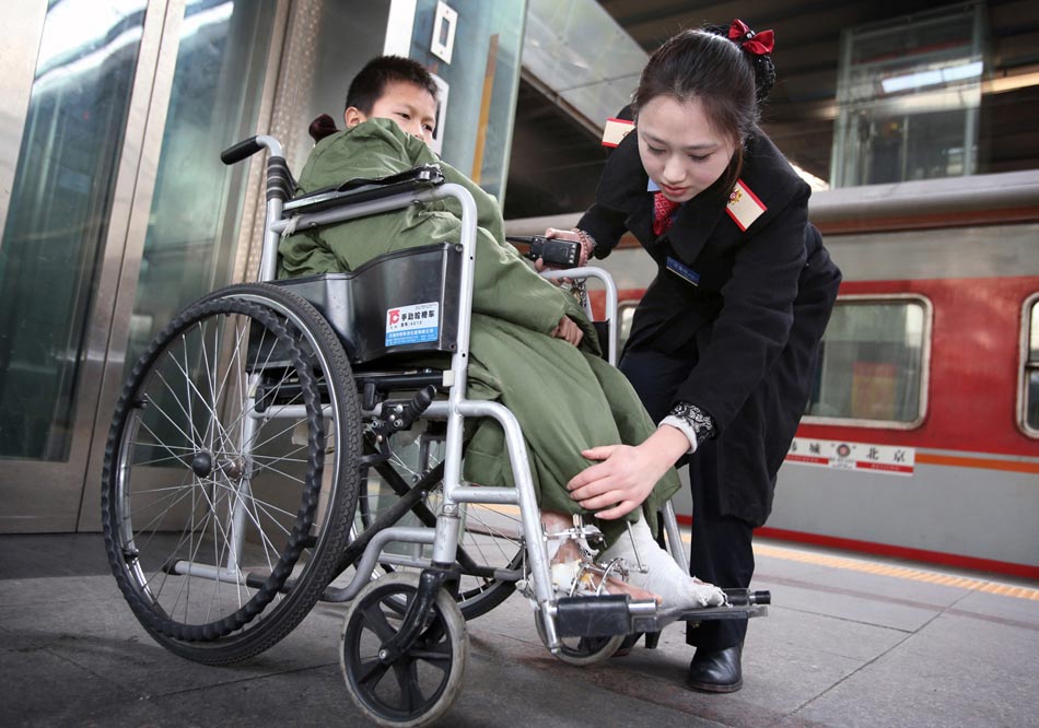 Lu Xuechun, member of Suping Service Team helps a kid who just received surgery on feet on Jan.25, 2013 at the platform of Beijing Railway station. The service team is named after the labor model Li Suping, and provides free pick-up service to the old, ill, disable and pregnant travelers around the clock. Now the service team has nine members. (Xinhua/Wan Xiang) 