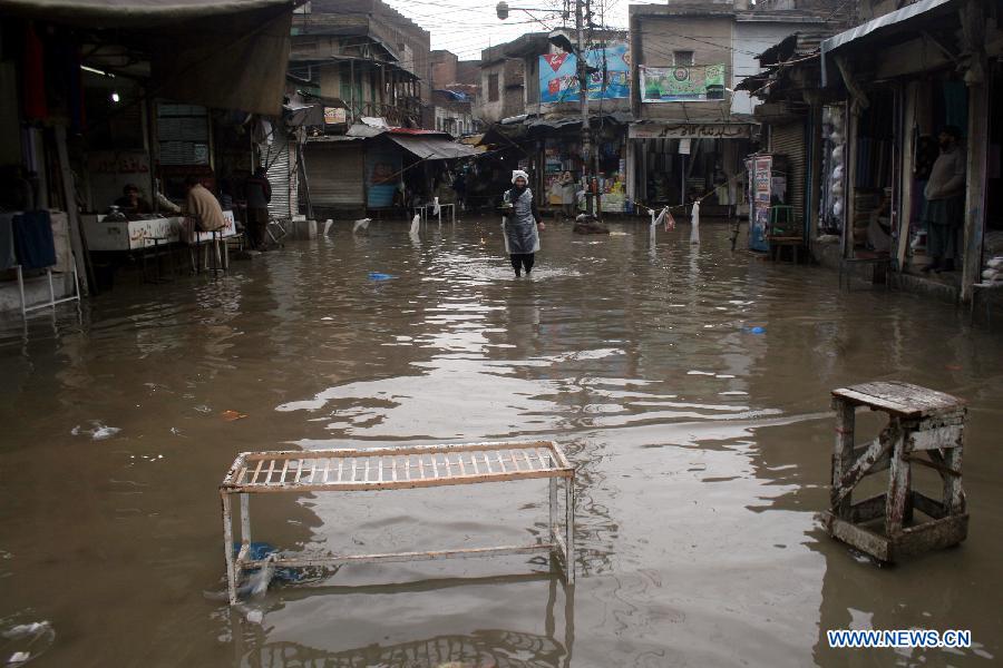 A man walks on a flooded street in northwest Pakistan's Peshawar Feb. 6, 2013. At least 17 people were killed, 31 injured and many others displaced after moderate to heavy rainfall lashed several areas of Pakistan over the last 72 hours, local TV Dunya reported on Tuesday. (Xinhua/Umar Qayyum)