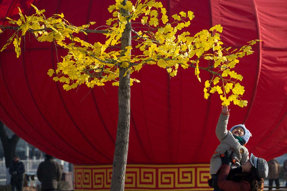 A boy and his mother play on a square decorated with a huge red lantern in Beijing's Shunyi district on Jan 26.