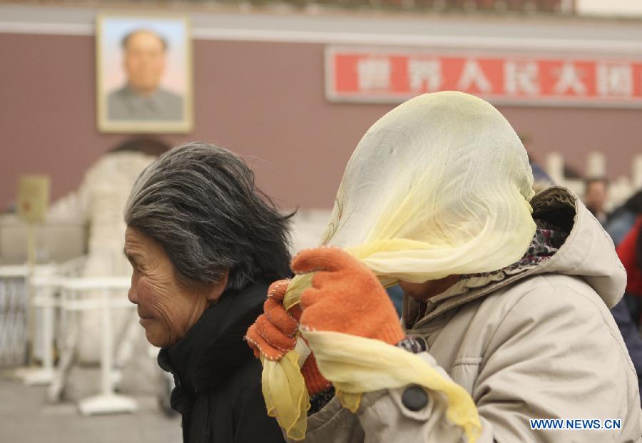 A pedestrian wears head scarf against wind and dust as she walks past the Tian'anmen in Beijing, capital of China, Feb. 28, 2013. Beijing was hit by heavy fog on Thursday morning. The fog led to reduced visibility and degenerated air quality. The city also issued high wind and haze alerts on the same day. (Xinhua/Liu Changlong)