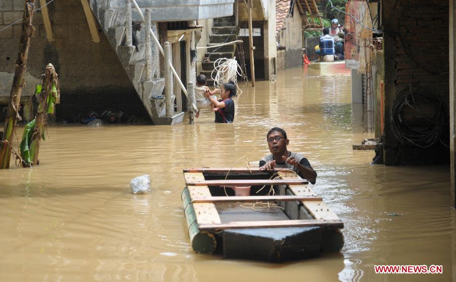  A man walks through a flooded area with a boat in Cawang, East Jakarta, Indonesia, March 5, 2013. The National Disaster Mitigation Agency (BNPB) on Tuesday warned that Jakarta could experience another big flood this week, as many areas in the city have already been swamped after the water level at Bogor's Katulampa dam reached 250 centimeters on Monday. (Xinhua/Zulkarnain) 