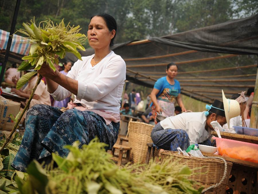 A woman in folk costumes arranges flower branches during a celebration marking the upcoming Water Splashing Festival in Mangshi, southwest China's Yunnan Province, April 11, 2013. The Water Splashing Festival, also the New Year of the Dai ethnic group, will last for three or four days. (Xinhua/Qin Lang)