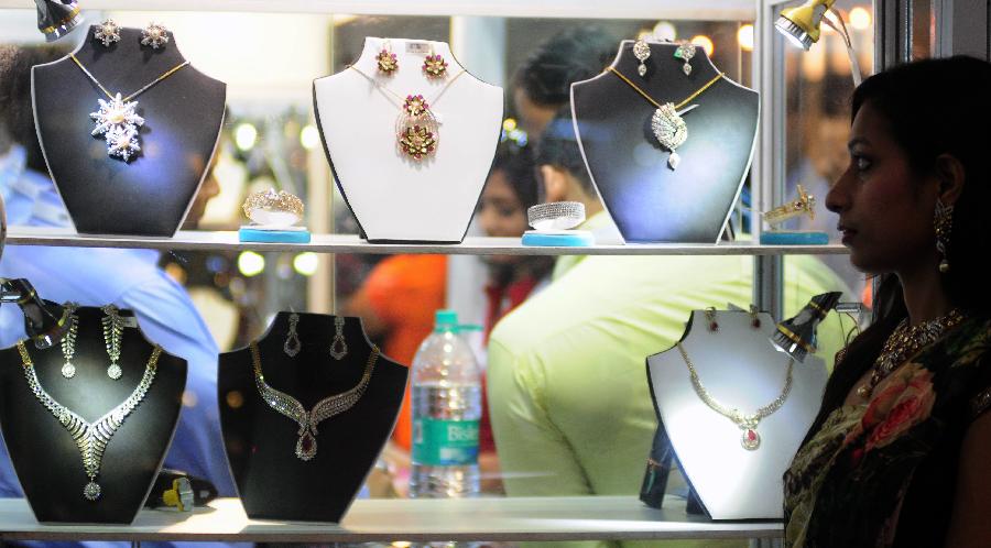 A visitor walks past jewellery on display during the India Gems and Jewellery Fair 2013 in New Delhi, India, April 12, 2013. (Xinhua/Partha Sarkar)