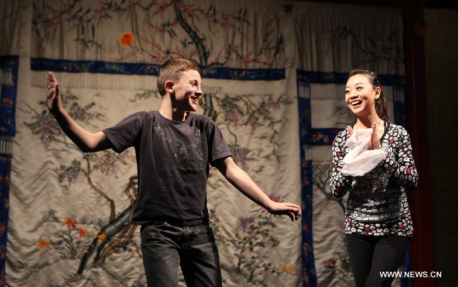 A boy (L) learns Peking Opera performance at the Temple Theatre Beijing Opera House in Beijing, capital of China, April 18, 2013. Students from an international school in Beijing participated in a public education activity named "the charm of Sheng, Dan, Jing, Chou in Peking Opera" on Thursday here. "Sheng","Dan","Jing" and "Chou" refer to different roles in Peking Opera. (Xinhua/Pan Siwei) 