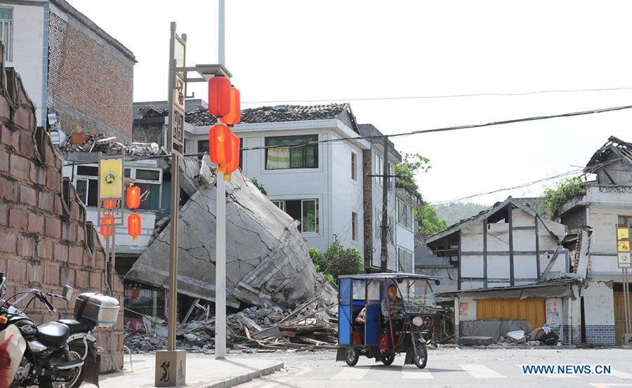 A local resident rides in front of collapsed houses in quake-hit Lushan County, Ya'an City, southwest China's Sichuan Province, April 20, 2013.  (Xinhua/Jin Xiaoming)