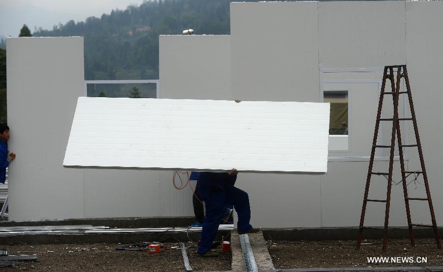 Prefabricated houses under construction are seen on the play ground of the middle school of Taiping Village in Lushan County of Ya'an City, southwest China's Sichuan Province, April 30, 2013. The earthquake hitting Lushan on April 20 has damaged the buildings of 357 schools in Ya'an, disturbing the teaching activities in 329 middle and primary schools. Local people built prefabricated houses for the school children to continue their lessons in recent days. (Xinhua/Jin Liangkuai)