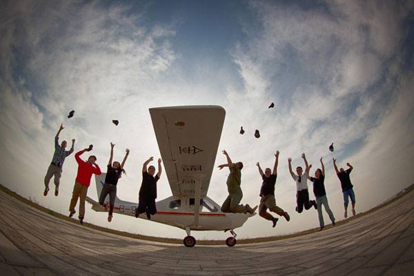 Flying enthusiasts jump for joy after taking to the skies at an airport in Huanghua, North China’s Hebei province, on May 1, 2013. During the May Day holiday, over 30 flying fans of various backgrounds and all with years of computer simulated flying experience came to Huanghua and experienced the real thing organized by an online forum of military fans. [Photo/Xinhua] 