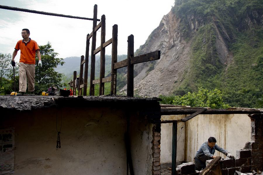 Villagers look for timber for house reconstruction and pull down dangerous houses in Xiangshuixi Village in Tianquan County, southwest China's Sichuan Province, May 18, 2013. Villagers who were affected by the earthquake that jolted the region on April 20 are rebuilding their houses with building materials recovered from the ruins. (Xinhua/Cui Xinyu)