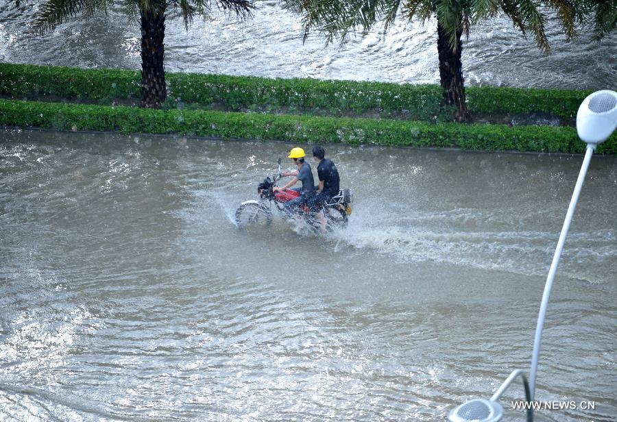 People ride in floods in Nanning City, south China's Guangxi Zhuang Autonomous Region, June 4, 2013. A heavy rainfall hit Nanning on Tuesday, and local meteorological authorities issued an orange alert for rainstorms. China has a four-color warning system for strong rain, with red being the most serious, followed by orange, yellow and blue. (Xinhua/Zhou Hu)