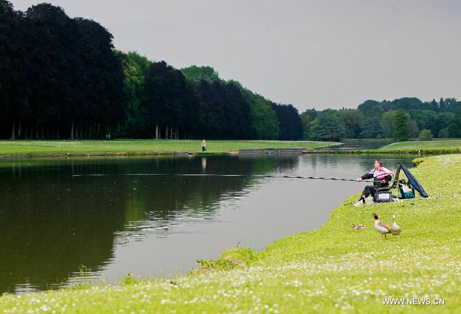 A man fishes at a park in the eastern suburbs of Brussels, capital of Belgium, on June 11, 2013. Local residents go to parks to enjoy the sunshine after experiencing a long and gloomy spring this year. (Xinhua/Zhou Lei)