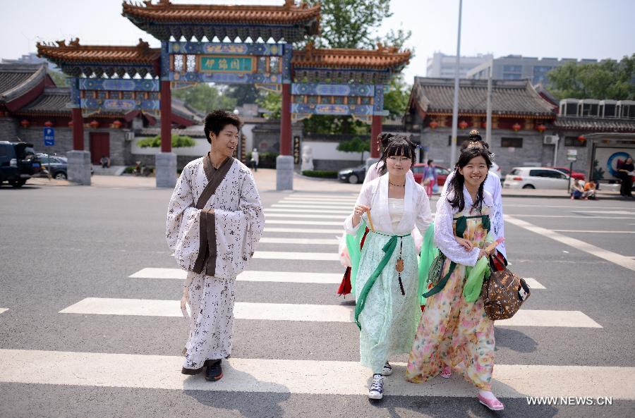 People wearing the archaic costumes typical of the Han Dynasty (202 BC - 221 AD) walk across a street during an event to commemorate Quyuan, a famous ancient official who drowned himself for finding no way to make his small hinterland kingdom better, and spend the holiday of Dragon Boat Festival in Beijing, China, June 12, 2013. (Xinhua/Wang Jianhua)  