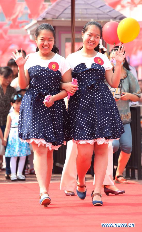 A pair of twins attends the 2013 Shandong (Weifang) First Twin Cultural Festival in Weifang, east China's Shandong Province, June 15, 2013. The festival, in which more than 60 pairs of twins and multiple births from Weifang City showed their talents and exchanged with each others, opened here on Saturday.(Xinhua/Zhang Chi) 