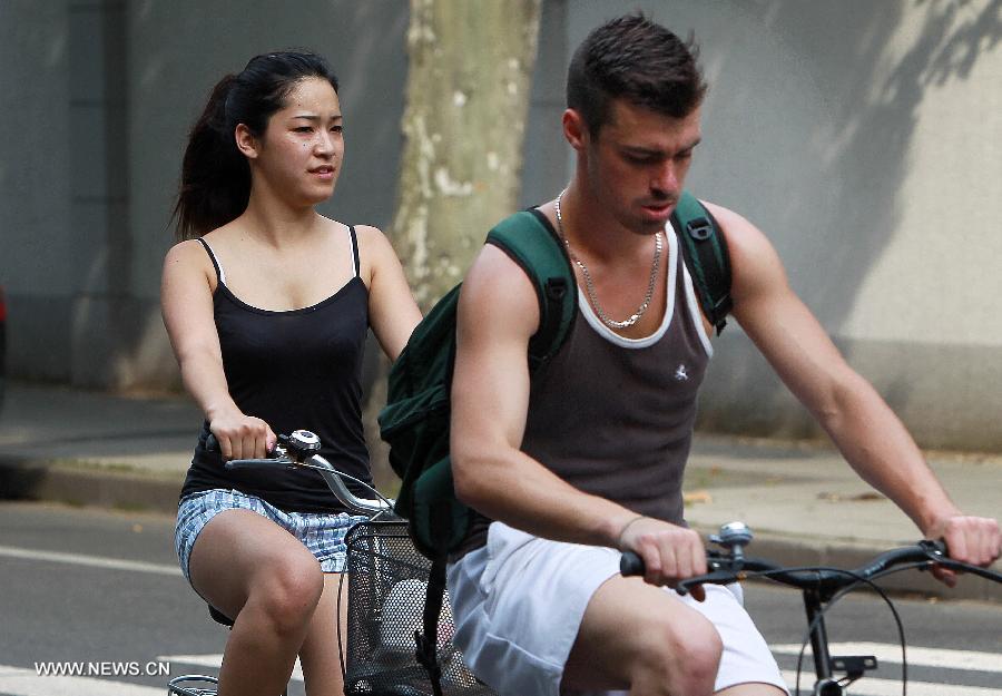 Citizens ride bicycles on Guangyuan West Road in Shanghai, east China, June 18, 2013. The highest temperature in Shanghai reached 37 degrees centigrade on June 18. (Xinhua/Ding Ting)