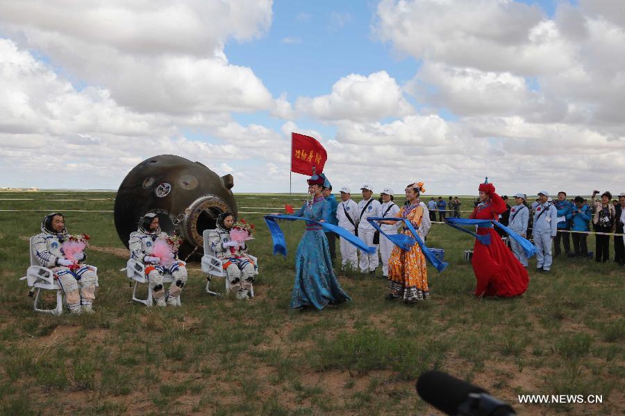 Astronauts Zhang Xiaoguang, Nie Haisheng and Wang Yaping (from left to right) receive congratulations after going out of the re-entry capsule of China's Shenzhou-10 spacecraft following its successful landing at the main landing site in north China's Inner Mongolia Autonomous Region on June 26, 2013. (Xinhua/Wang Jianmin)