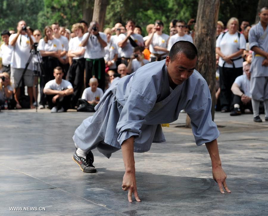 Tourists watch the performance of a monk at Shaolin Temple at the foot of the Songshan Mountain in Dengfeng City, central China's Henan Province, July 3, 2013. The Shaolin Temple entered a peak tourism season recently with the coming of summer vacation. (Xinhua/Li Bo) 