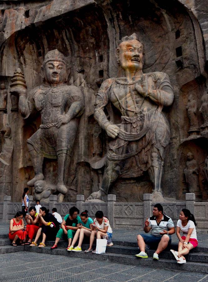 Tourists rest in the scenic area of the Longmen Grottoes in Luoyang, central China's Henan Province, July 7, 2013. Recently, high temperature hit central China. Tourists relaxed in cool places in the Longmen Grottoes to avoid themselves from scorching weather. (Xinhua/Wang Song)