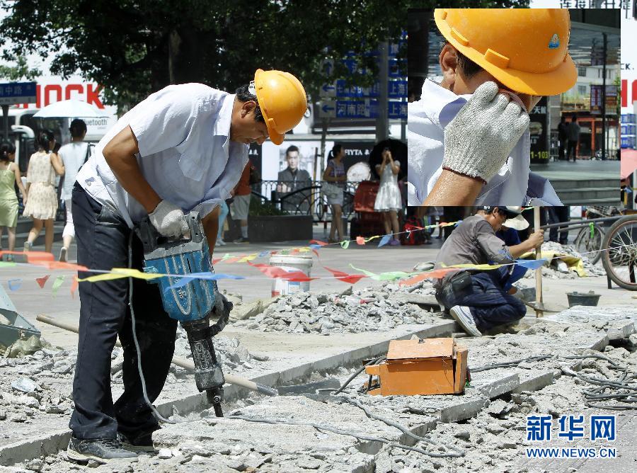 Cao Xiaohua, a road maintenance worker, works in Henanzhong Road in Shanghai, July 3, 2013. Shanghai issued yellow warning of high temperature on July 3, 2013. The maximum temperature exceeded 35 degrees Celsius. (Xinhua/Ding Ding) 