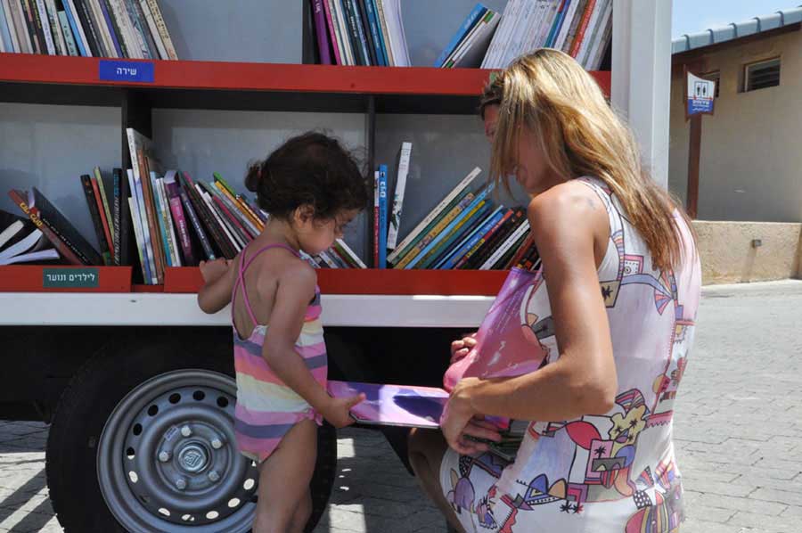 A mother chooses a book for her daughter at a beach library in Tel Aviv-Yafo on Tuesday, July 9, 2013. [Photo: CRIENGLISH.com / Zhang Jin]  