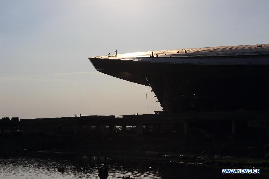 Laborers work atop the Olympic sports center under construction in heat in Shaoxing City, east China's Zhejiang Province, July 10, 2013. (Xinhua/Li Ruichang)