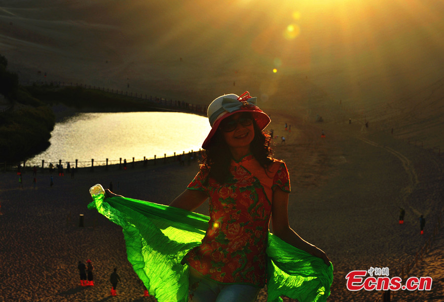 A visitor poses for photos at the scenic spot of Crescent Lake in Dunhuang City of Northwest China's Gansu Province. (CNS/Jia Guorong)