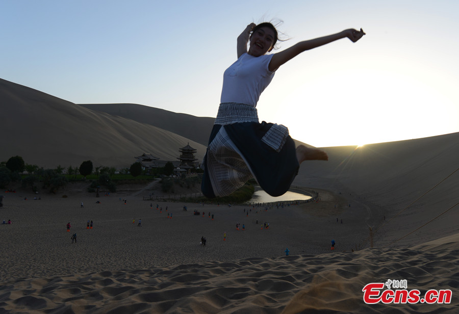 A visitor poses for photos at the scenic spot of Crescent Lake in Dunhuang City of Northwest China's Gansu Province. (CNS/Jia Guorong)