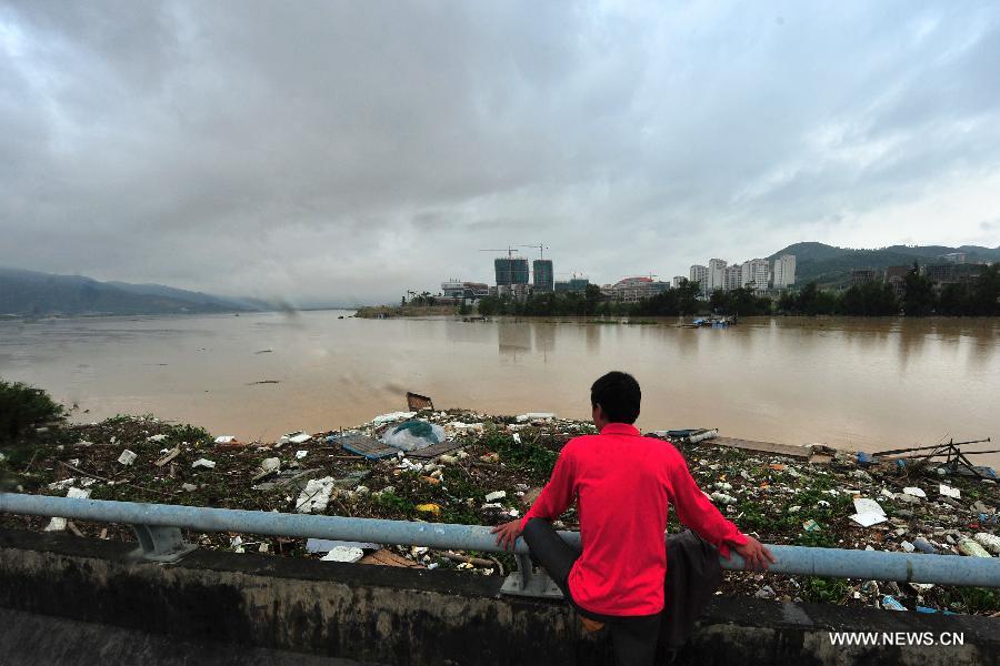 A fisherman watches loads of waste coming with flood from the upstream at Zhuoqi sea wall in Longhai of Zhangzhou City, southeast China's Fujian Province, July 19, 2013. Tropical storm Cimaron made its landfall in Fujian Thursday evening, bringing heavy rain and strong gales to southern part of the province. Xiamen, Zhangzhou, Quanzhou and Putian were severely affected by the storm, with the rainfall in some regions like Longhai reaching 520 millimeters on Friday. About 123,000 residents were afflicted by the storm and no casualties have been reported yet. (Xinhua/Wei Peiquan) 