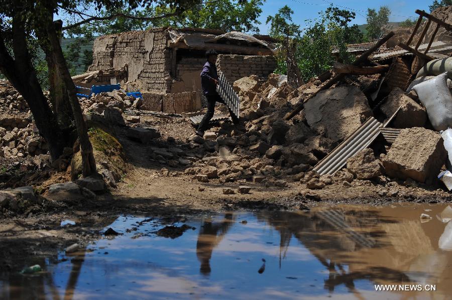 A villager searches for available articles at his quake-hit home in Yongxing Village of Minxian County, northwest China's Gansu Province, July 23, 2013. The death toll has climbed to 94 in the 6.6-magnitude earthquake which jolted a juncture region of Minxian County and Zhangxian County in Dingxi City Monday morning. (Xinhua/Liu Xiao)