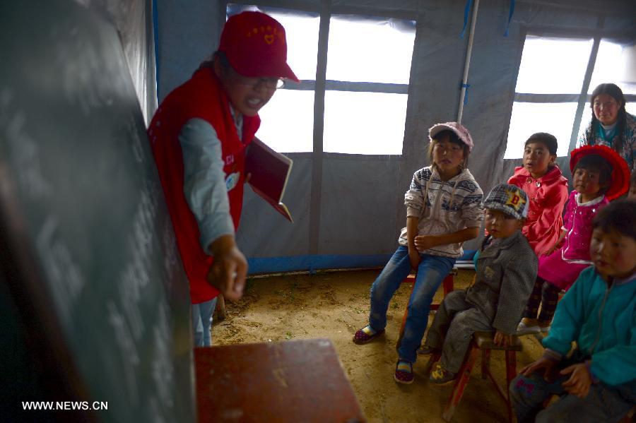 A volunteer teaches children in a "Tent School" in quake-stricken Yongxing Village of Minxian County, northwest China's Gansu Province, July 24, 2013. 10 university student volunteers teach various courses for those in need in the "Tent School" in quake-stricken Yongxing Village on Wednesday. (Xinhua/Zhang Meng)