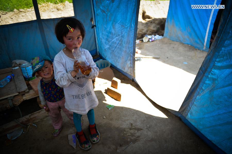 A girl wears a pair of oversized shoes at a makeshift settlement in Meichuan Town of quake-hit Minxian County, northwest China's Gansu Province, July 23, 2013. A 6.6-magnitude quake hit northwest China's Gansu Province on Monday morning, leaving 95 dead and 1,001 injured. (Xinhua/Liu Xiao) 