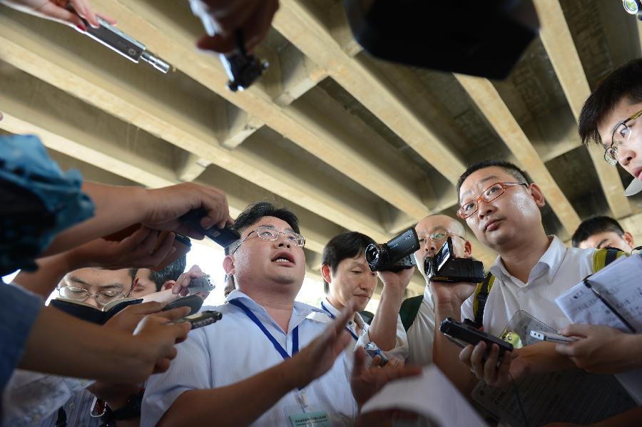 A Japanese journalist (C) introduces the trial process to media staff members outside the Shijiazhuang Intermediate People's Court after the trial in Shijiazhuang, north China's Hebei Province, July 30, 2013. The court on Tuesday opened a trial for a man who allegedly added poison to frozen dumplings that sickened four Chinese and nine Japanese citizens in 2008. (Xinhua/Wang Min)