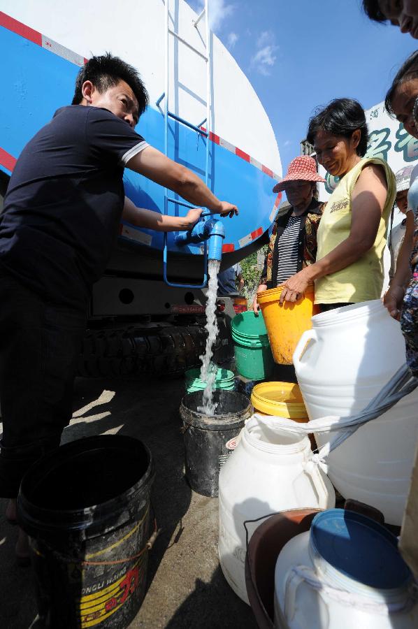 Local residents get water delivered by government in the Jinba Village of Jinsha County, southwest China's Guizhou Province, July 31, 2013. Lingering droughts in Guizhou have affected more than 12 million people. Over 2 million people lack adequate supplies of drinking water, and a total of 847,300 hectares of farmland is damaged by the drought. (Xinhua/Yang Ying)